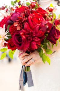 closeup photo of bride holding red rose bouquet