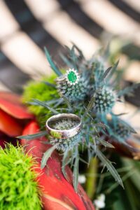 emerald engagement ring and man's wedding ring on flowers