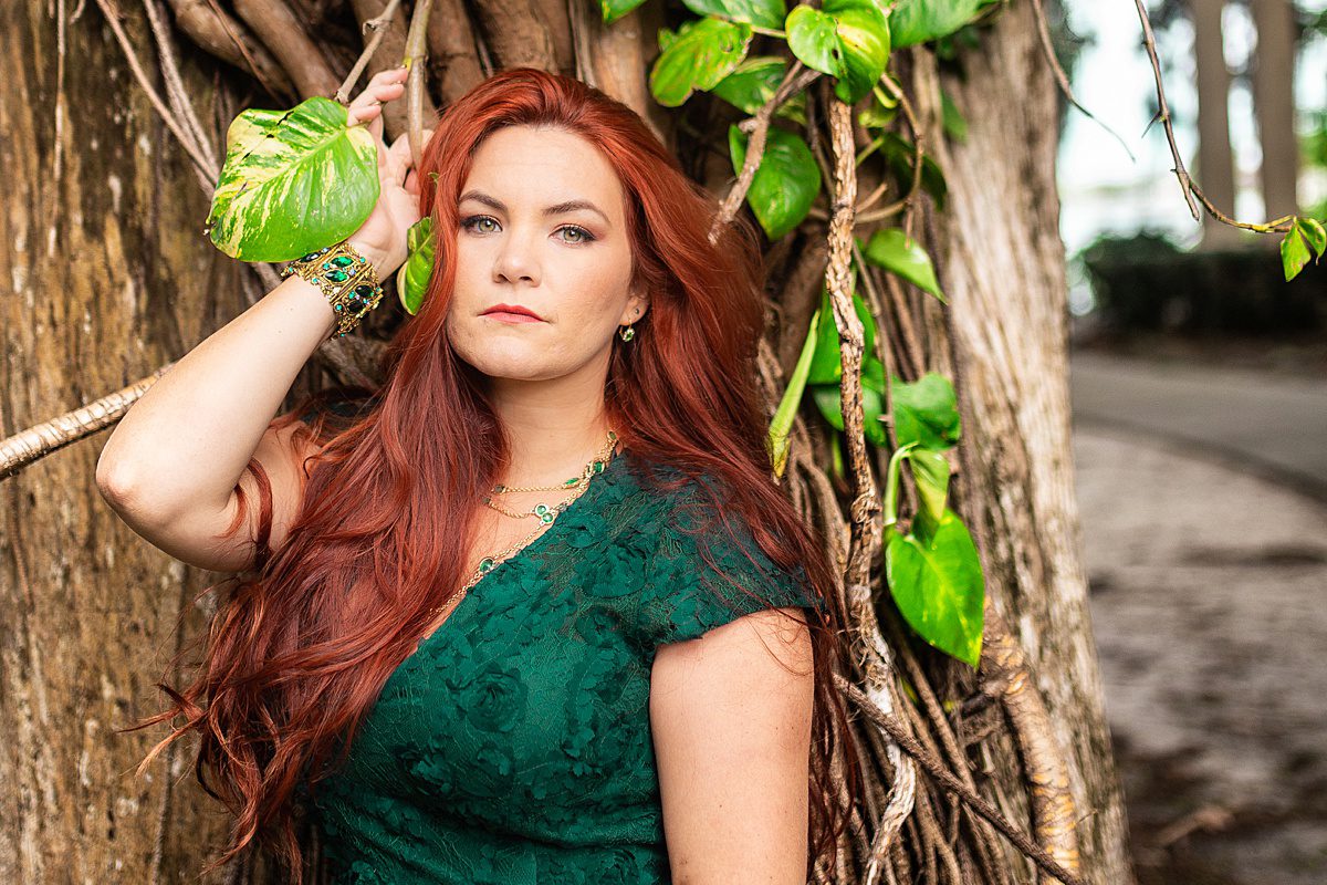 bride with red hair in emerald green dress in front of monstera vines and cypress tree at kraft azalea garden in winter park