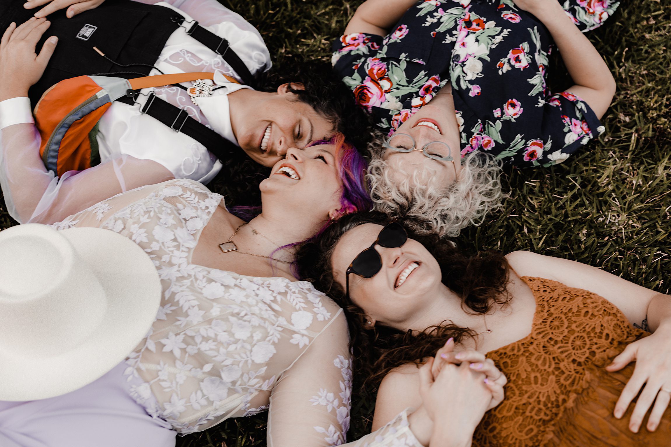 four sisters laying in the grass laughing together at the garden club of jacksonville wedding
