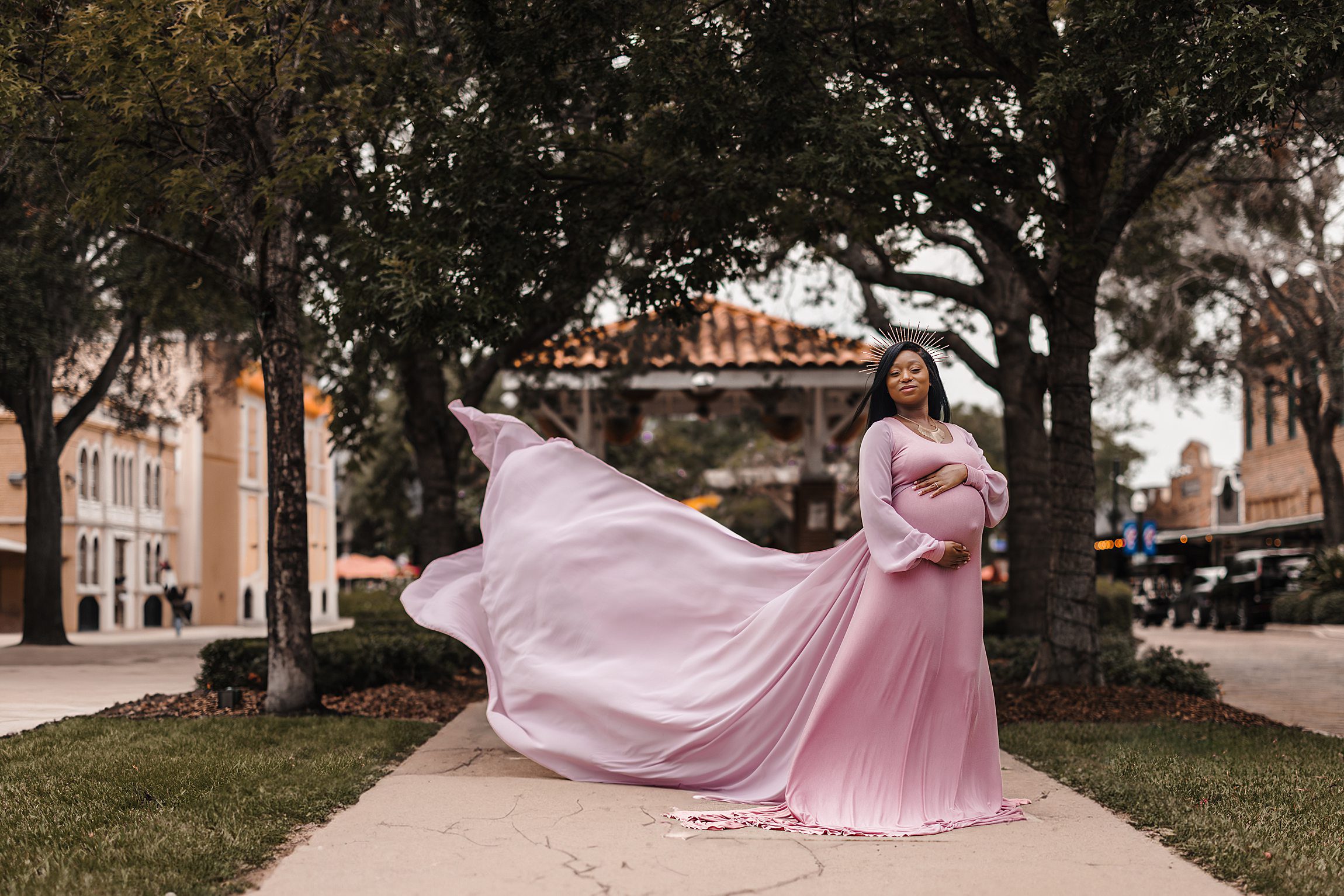 Pregnant black woman with a flowing dress standing on the sidewalk in winter garden florida