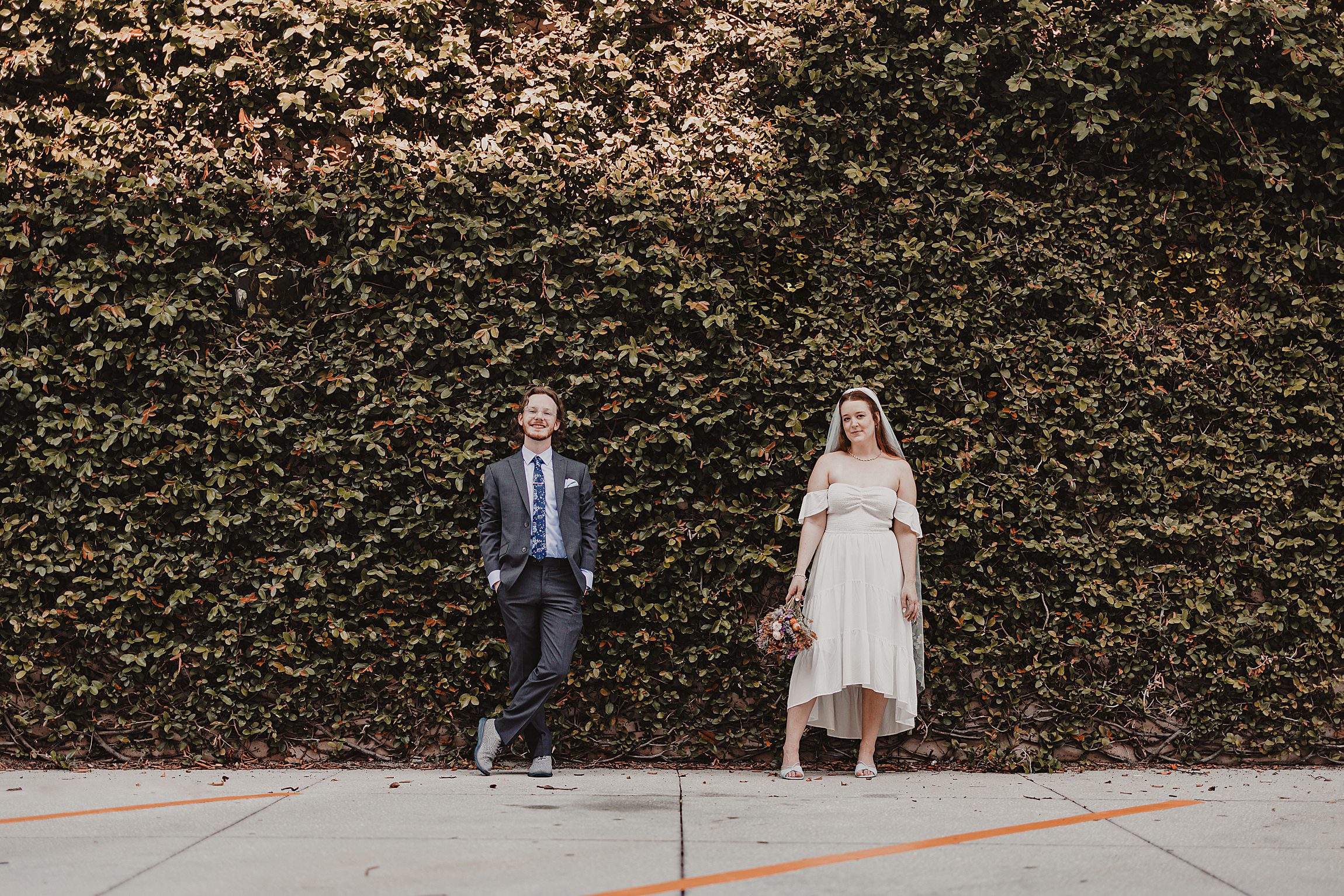 couple poses in front of a plant wall after getting married at the orange county courthouse in downtown orlando