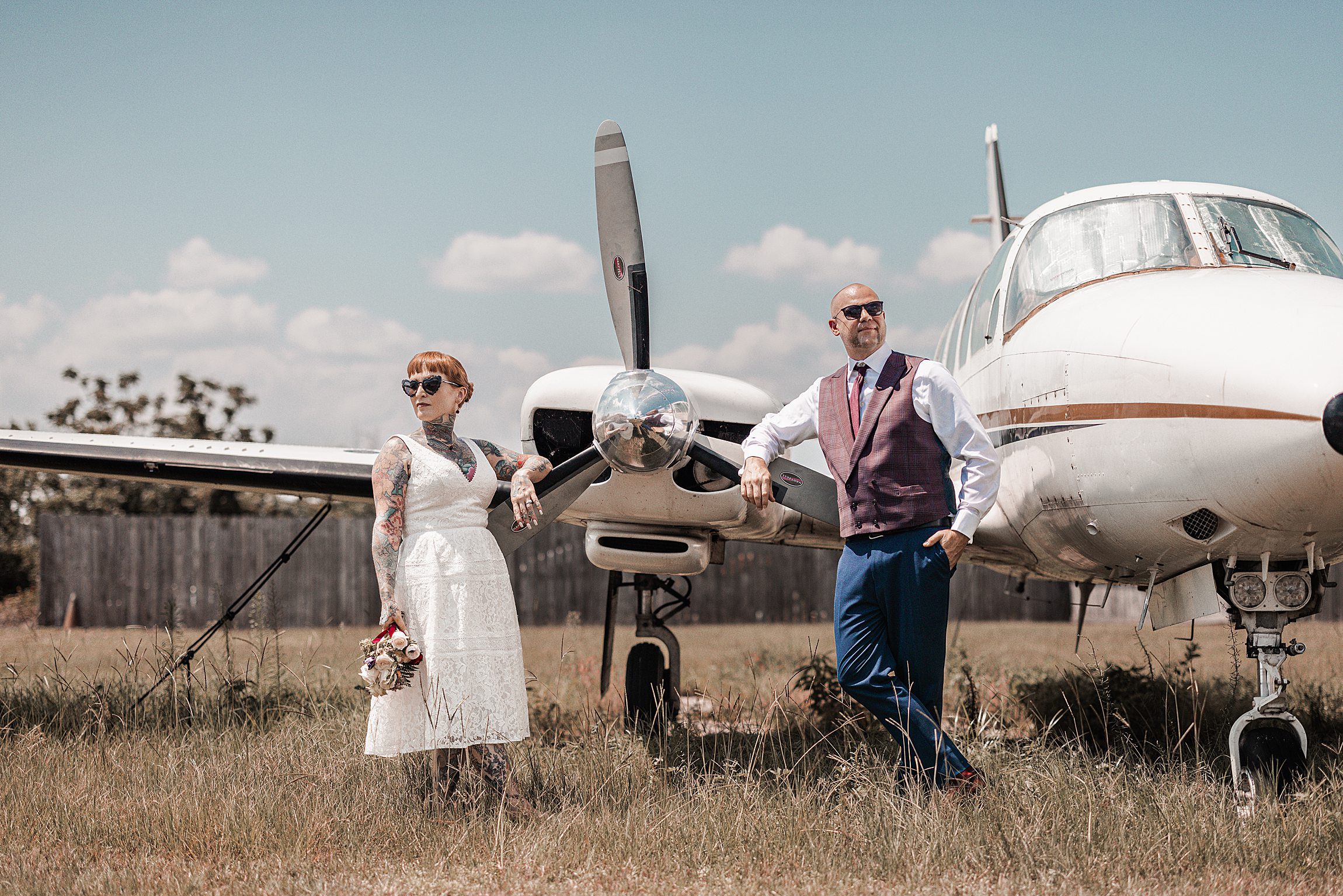 A newly married couple stand in front of a small private plane during their wedding reception at the orlando apopka airport.