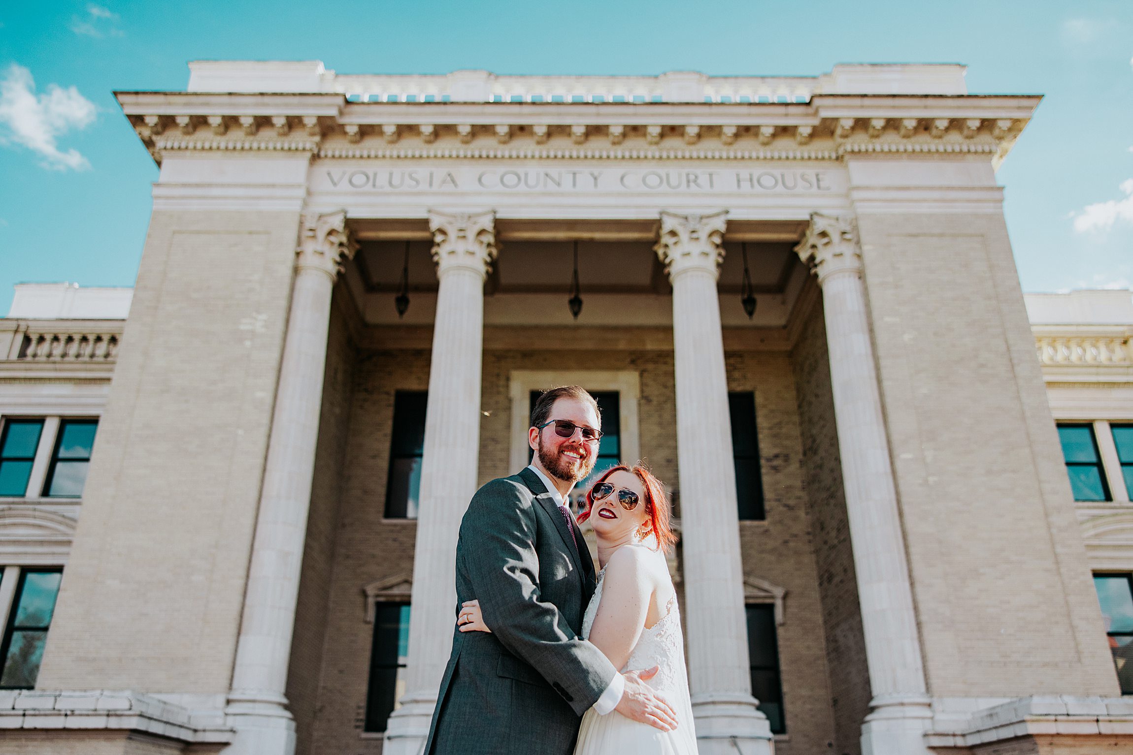 straight couple posing in front of the old volusia county courthouse after their civil wedding ceremony