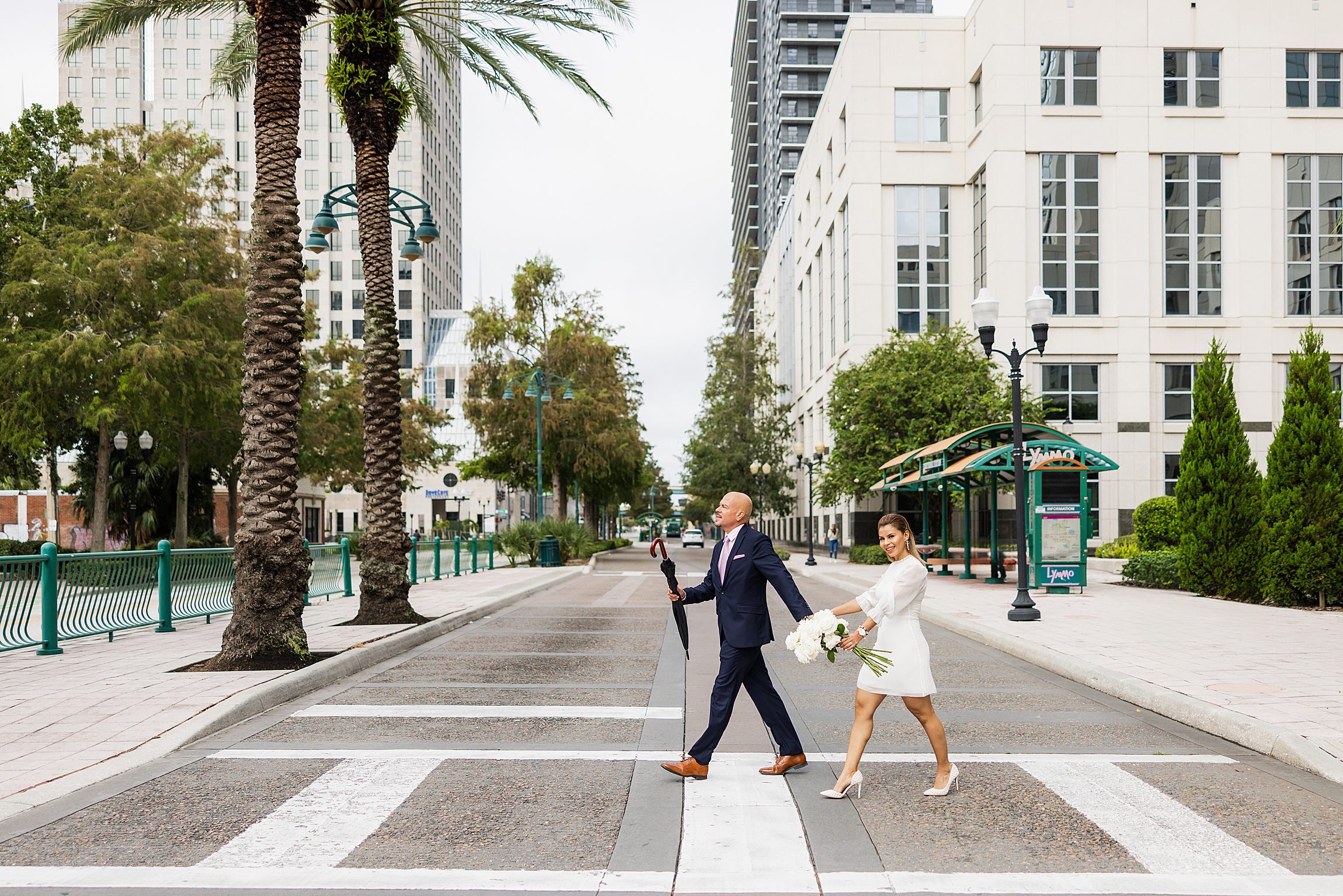 couple walking across the street in downtown orlando after their elopement at the orange county courthouse