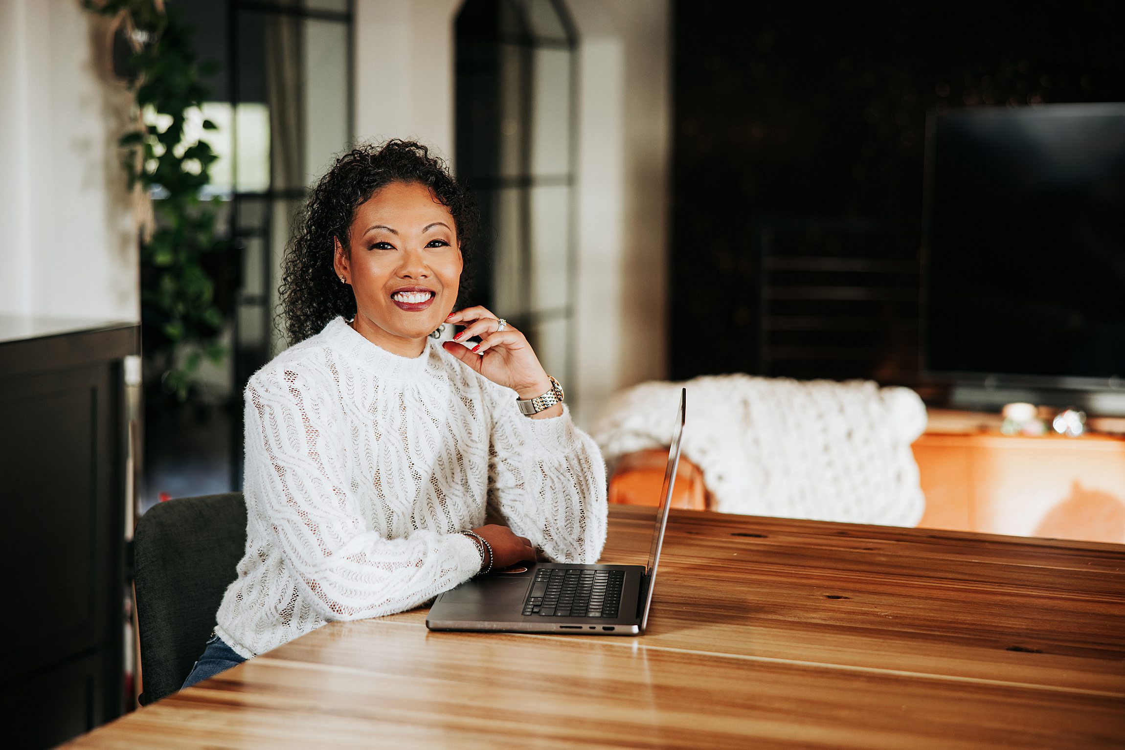 smiling woman of color sitting at a table with her computer