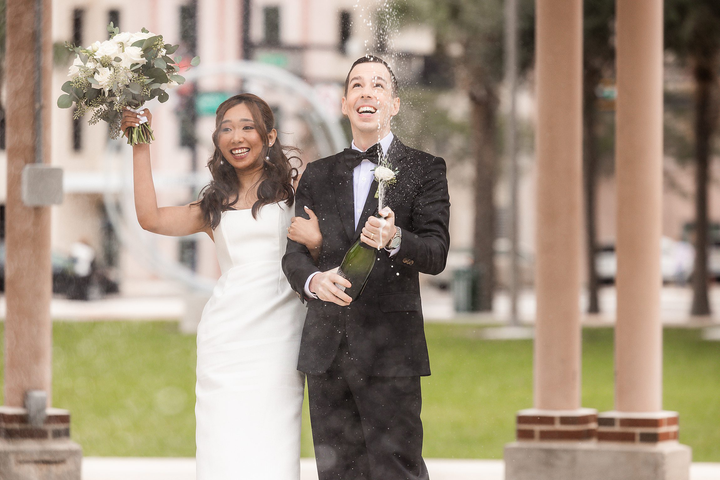 couple popping a bottle of champagne after their elopement wedding in downtown tampa
