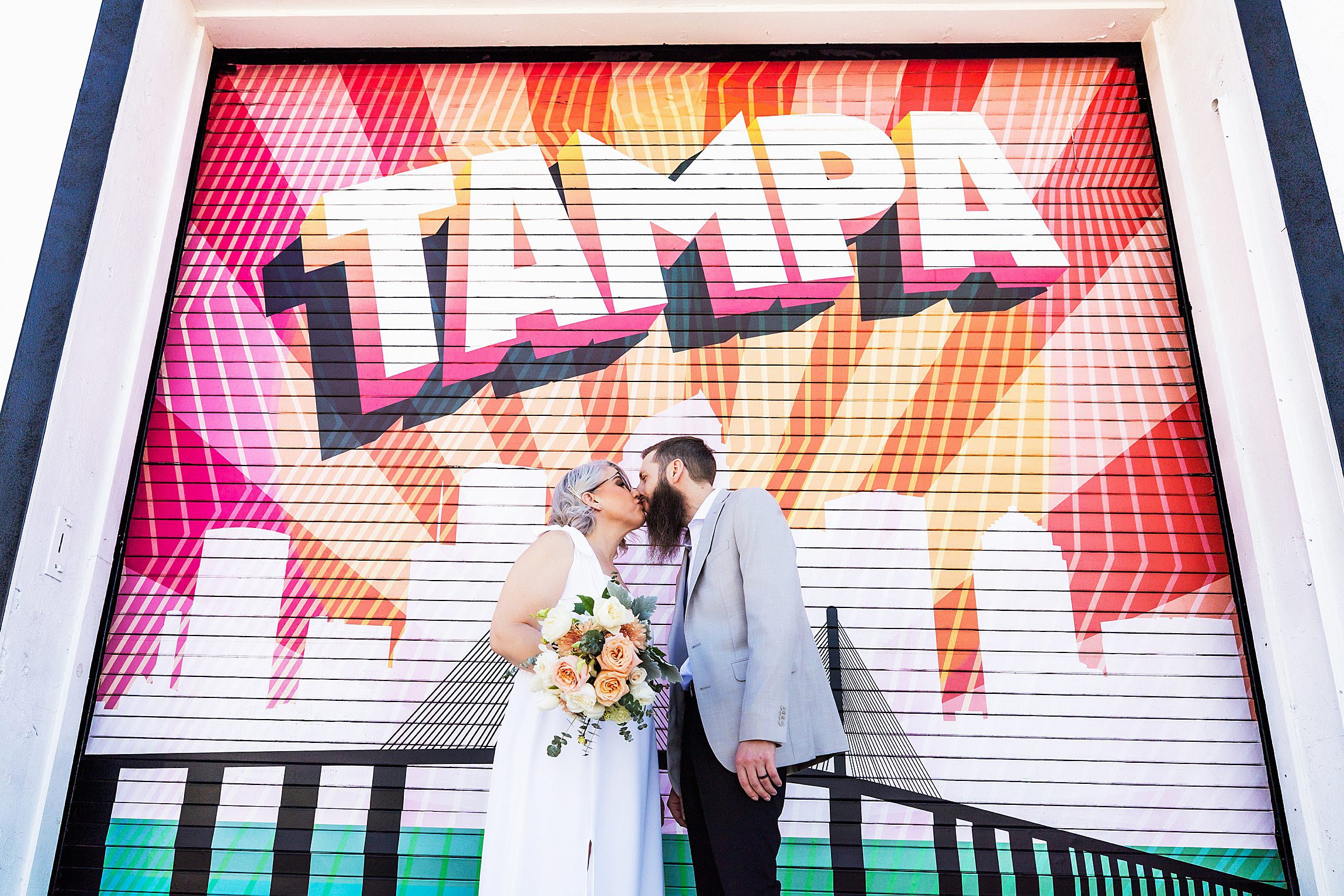 couple kissing in front of the tampa mural after getting married at the hillsborough county courthouse