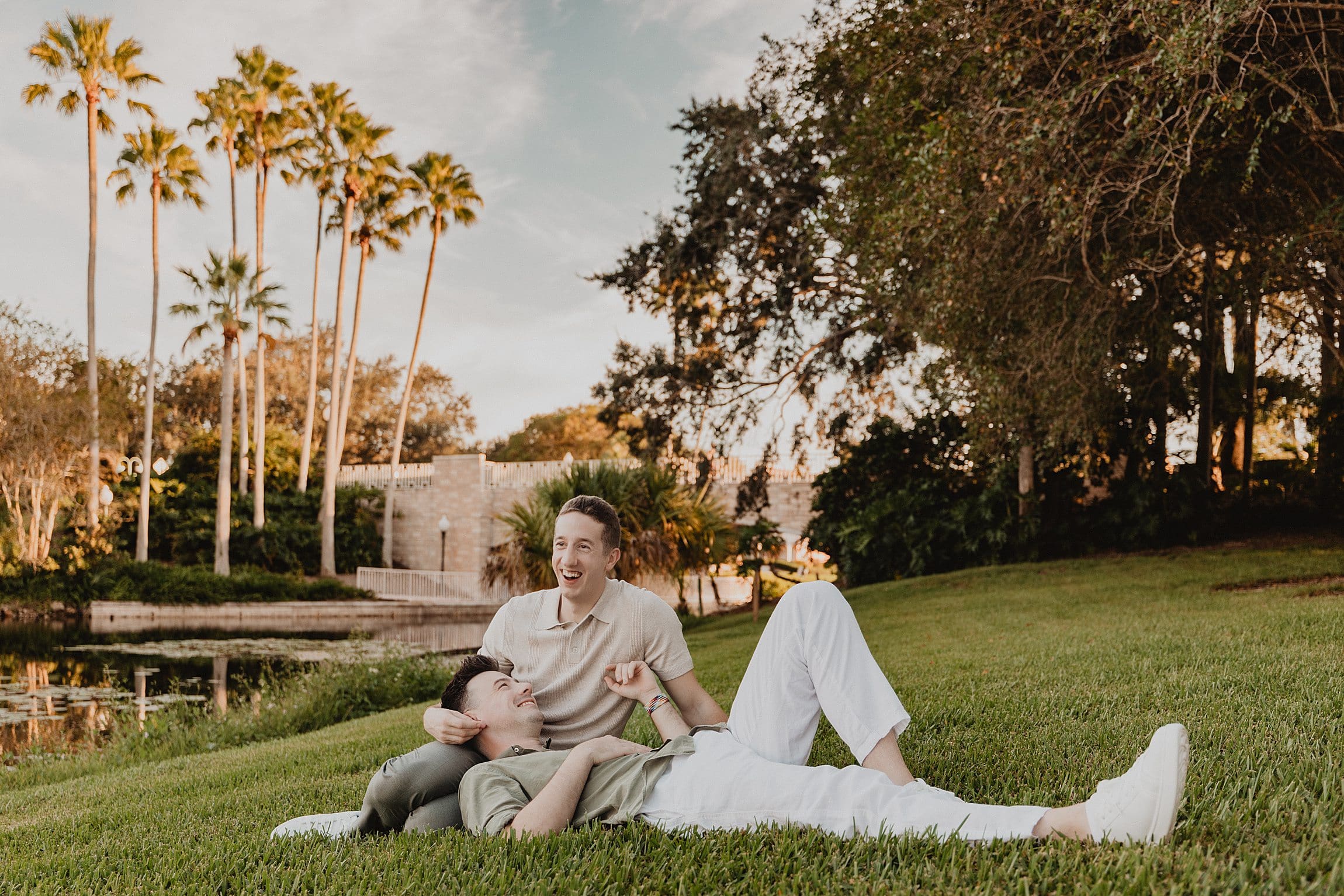 LGBTQIA+ elopement portrait of two grooms wearing casual tan and brown outfits on a grassy lawn at sunset at an Orlando Florida resort, captured by Gracie May Photography
