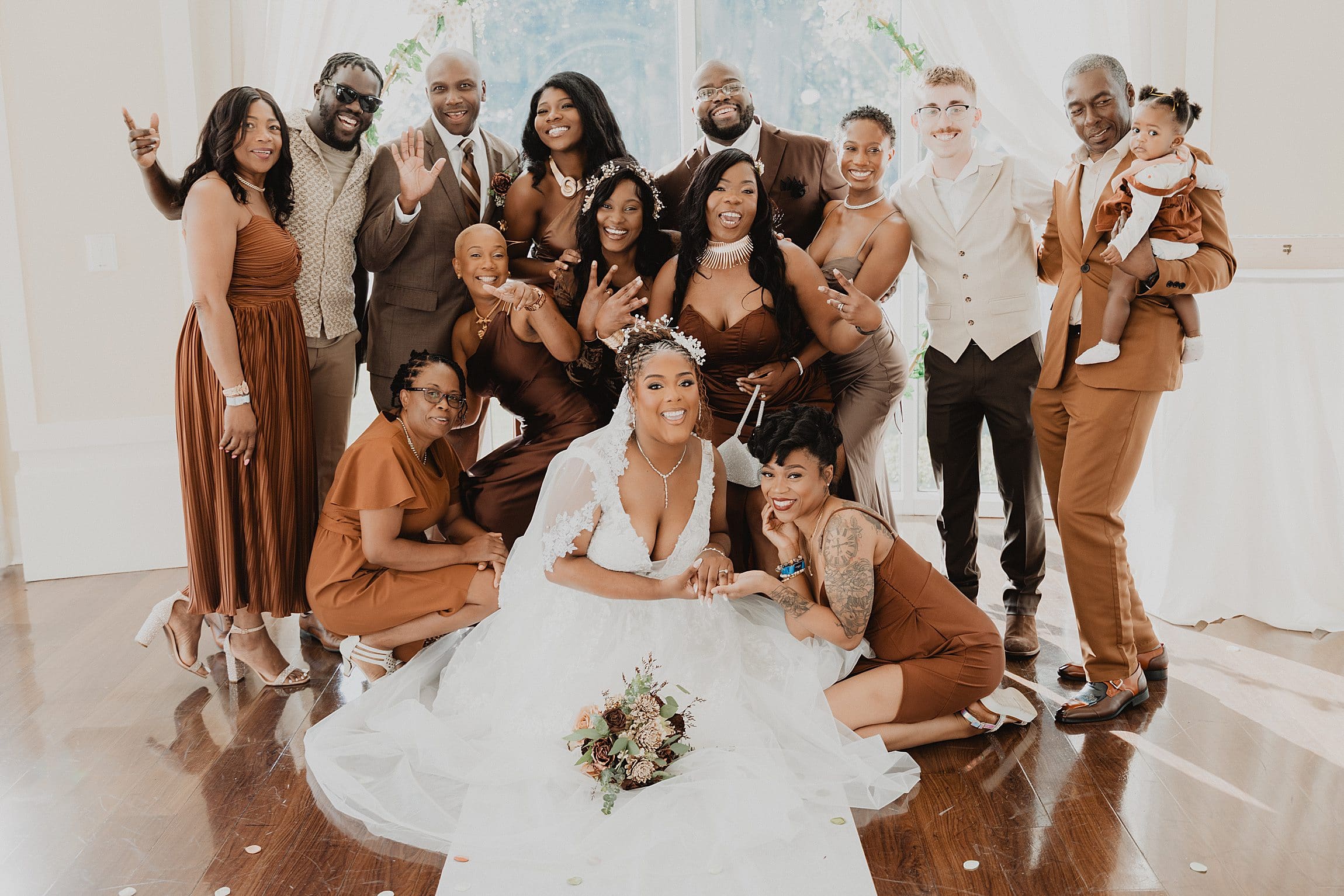 bride and groom with their family and wedding party all wearing shades of brown pose in the rotunda at Lake Mary Events Center in Florida, captured by Gracie May Photography