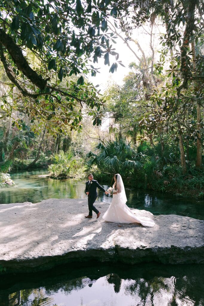 bride and groom during their intimate elopement in front of trees and the river at Kelly Park Rock Springs in Apopka Florida