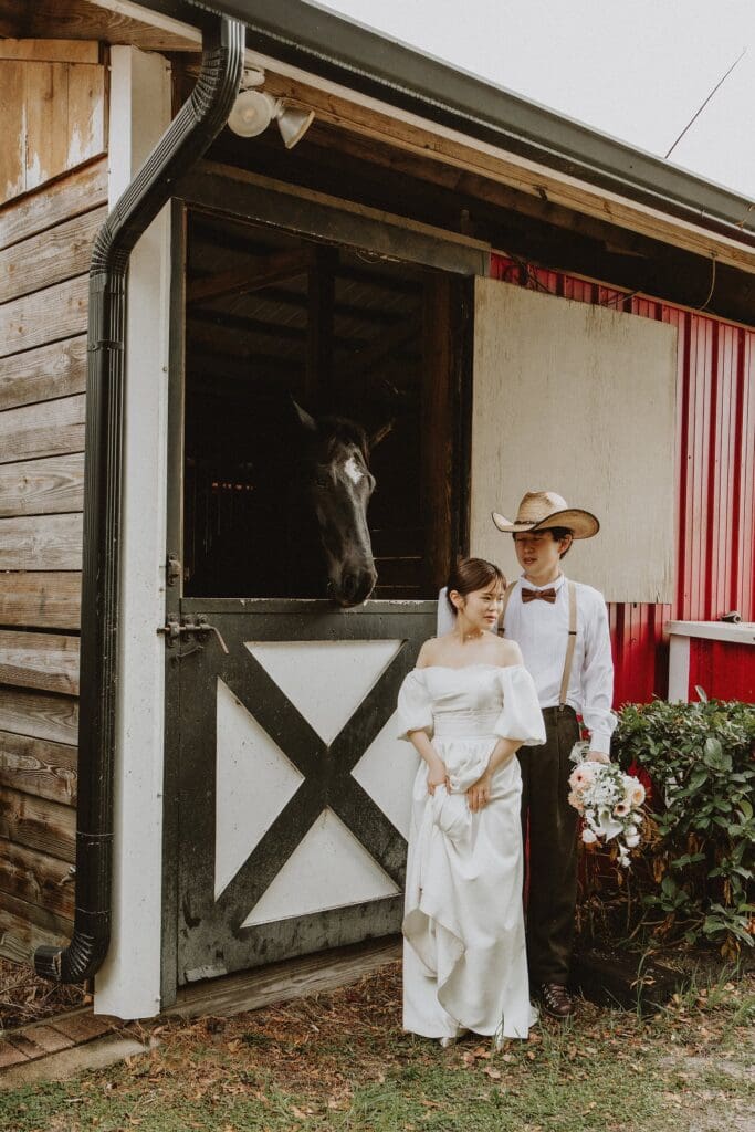 bride and groom in a wedding dress and western wear in front of the barn at Horsepower Ranch in Geneva, Florida, captured by Gracie May Photography