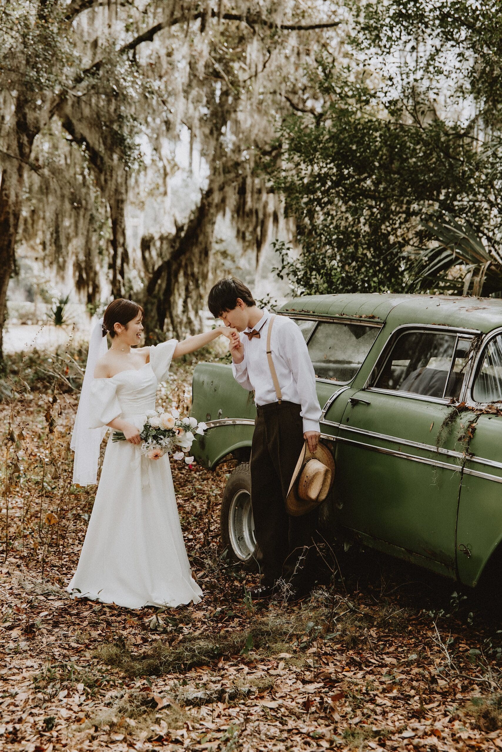 groom kissing his bride's hand in front of a vintage car at Horsepower Ranch in Geneva, Florida, captured by Gracie May Photography