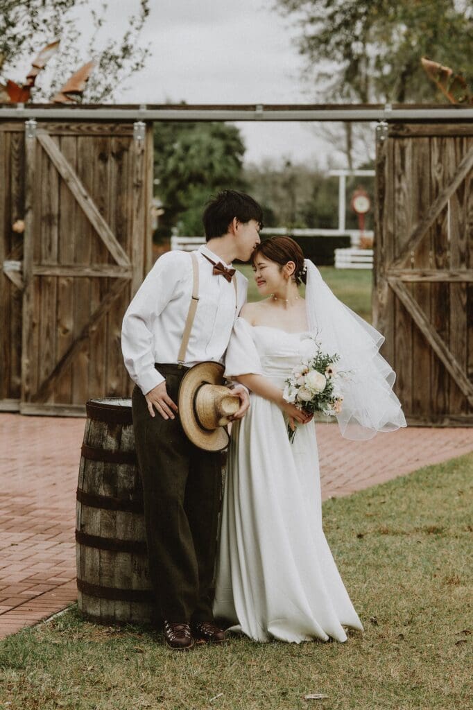 bride and groom in a wedding dress and western wear posing intimately in front of barn doors at Horsepower Ranch in Geneva, Florida, captured by Gracie May Photography