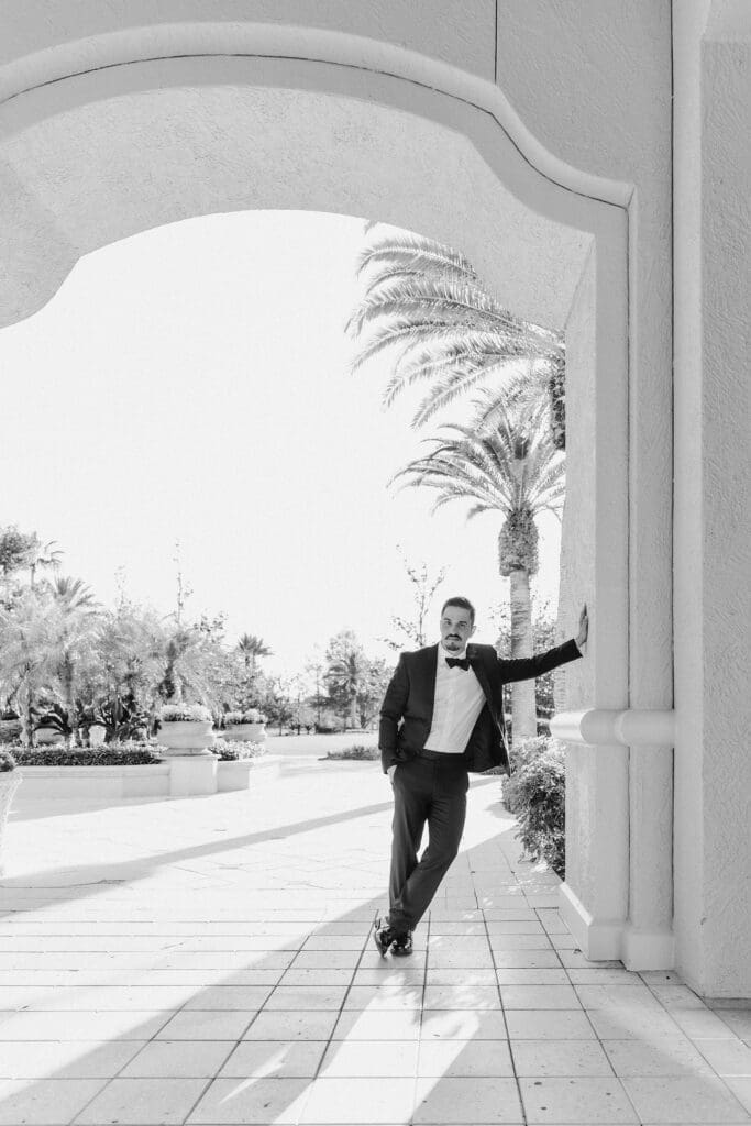 b&w photo of a groom in a black tux leaning against a wall at the ritz carlton orlando