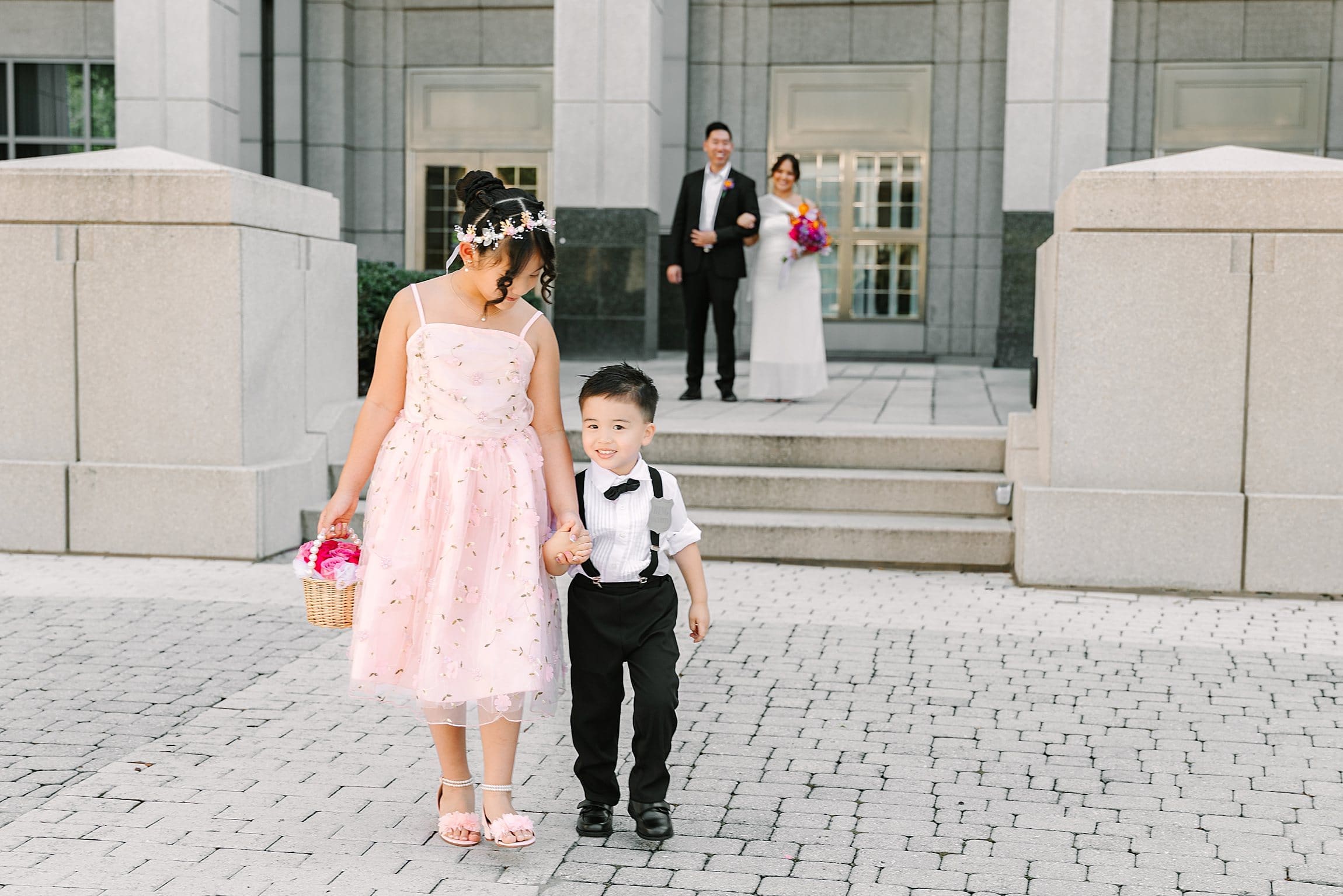 bride and groom smile and watch their two children in front of the Orange County Courthouse in Orlando after their courthouse wedding, captured by Gracie May Photography.