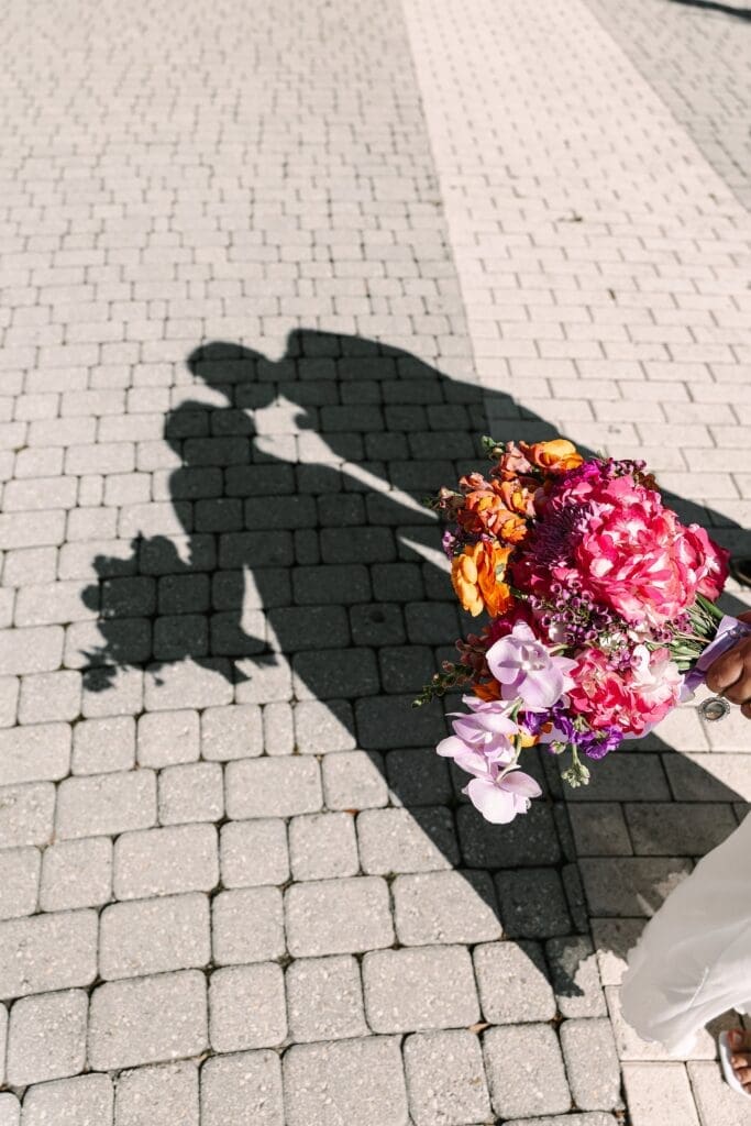 bride and groom's shadow's kissing in the background of a bright spring bouquet at the Orange County Courthouse in Orlando, captured by Gracie May Photography.