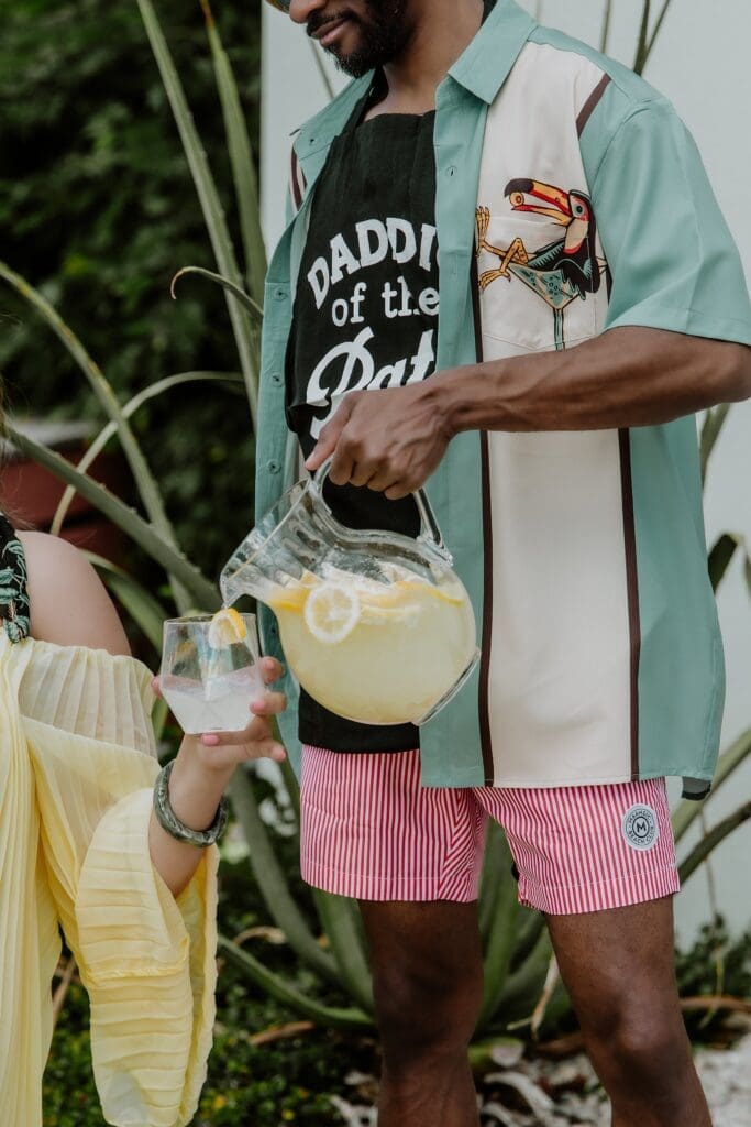 man pouring lemonade during a retro lavender pregnancy maternity photoshoot captured by Gracie May Photography