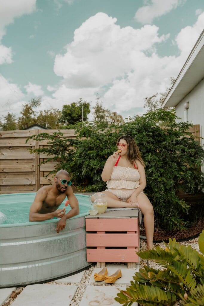 pregnant woman and man posing in a pool during their retro lavender pregnancy maternity photoshoot captured by Gracie May Photography