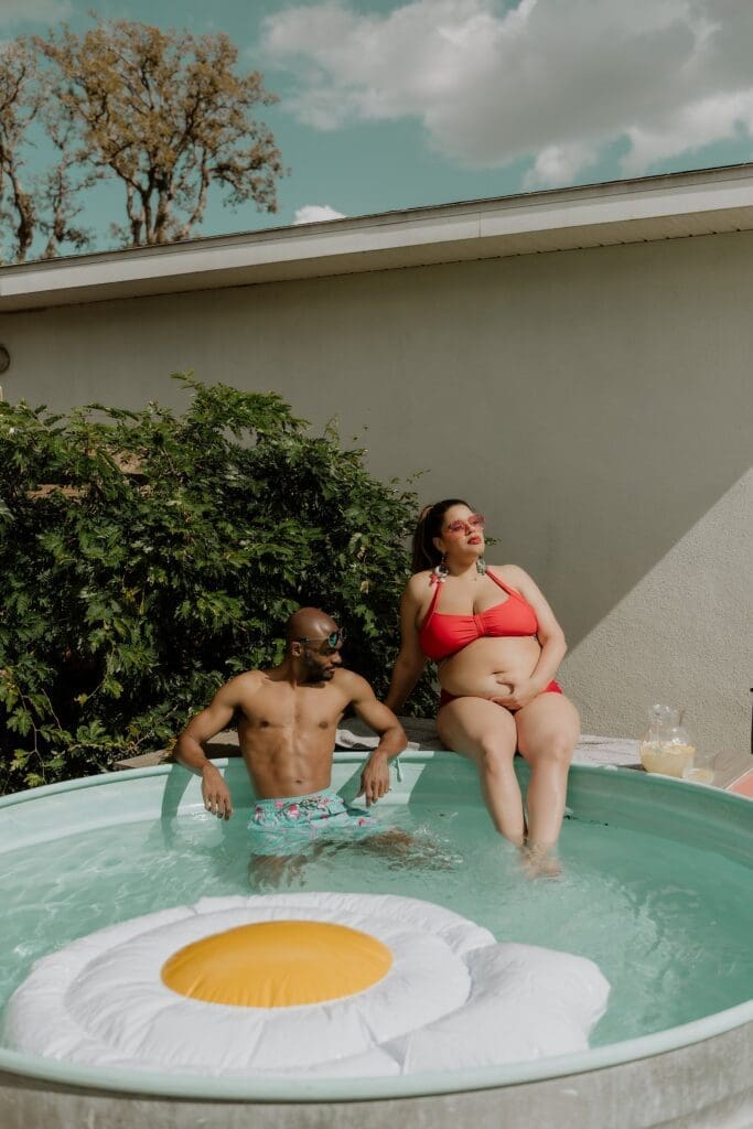 pregnant woman and man posing in a pool during their retro lavender pregnancy maternity photoshoot captured by Gracie May Photography