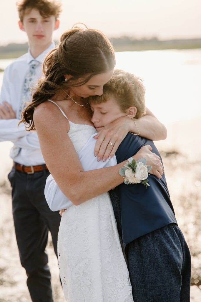 bride kissing her son the dock at Lavender on the Lake in St Cloud, Florida, during a micro wedding ceremony captured by Gracie May Photography