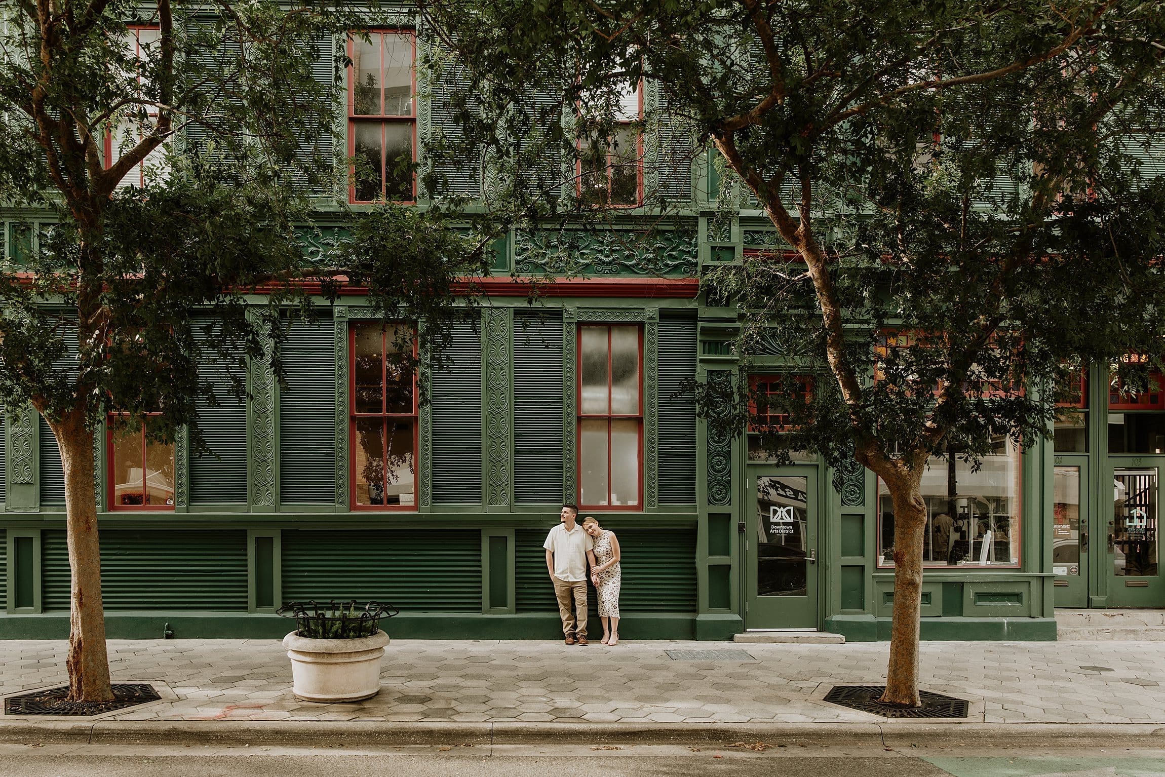 a couple resting against the green walls of the cityarts building in downtown orlando during their engagement session