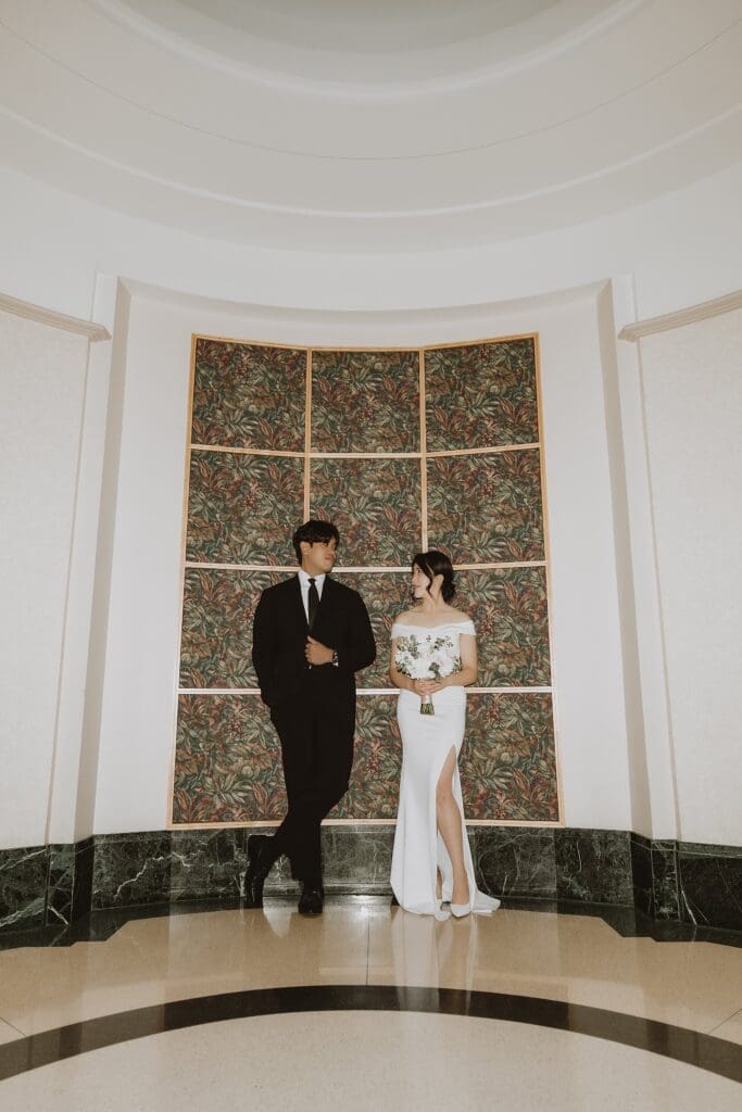 bride and groom stand in front of a patterned wall inside the Orlando Orange County Courthouse, captured by Gracie May Photography