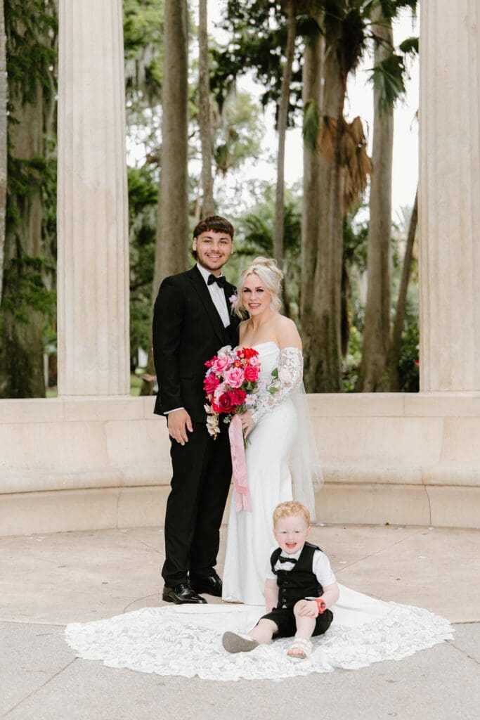 bride and groom with their toddler at an elopement at the Exedra Monument at Kraft Azalea Garden in Winter Park, Florida, captured by Gracie May Photography