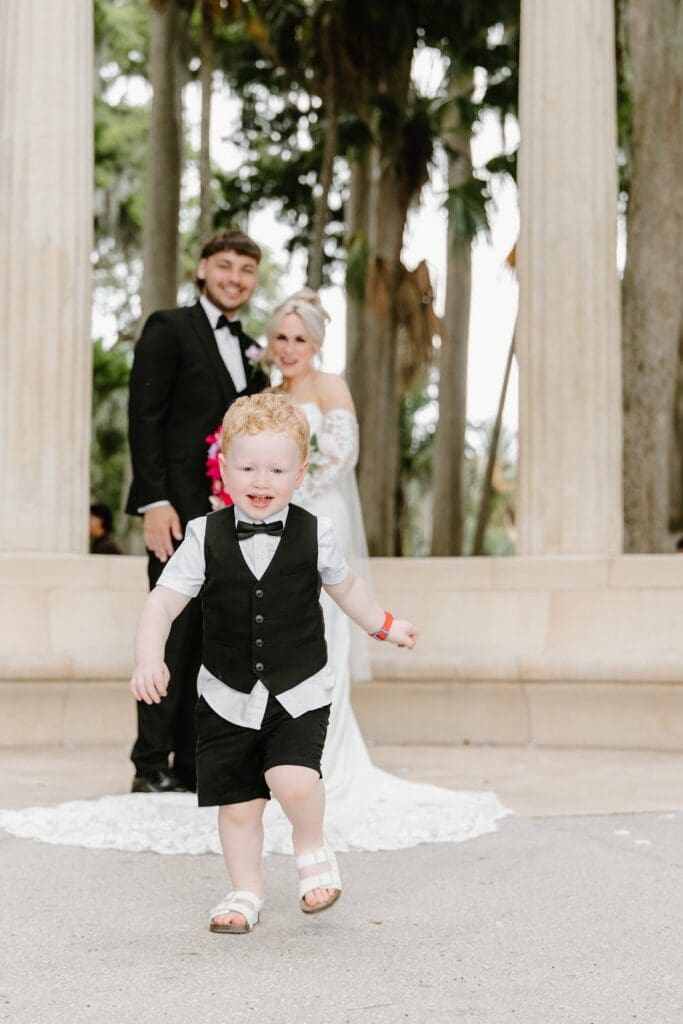 bride and groom with their toddler at an elopement at the Exedra Monument at Kraft Azalea Garden in Winter Park, Florida, captured by Gracie May Photography