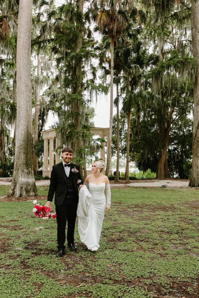 bride and groom wearing classic black and white wedding attire with a bold red and pink bouquet at an elopement at Kraft Azalea Garden in Winter Park, Florida, captured by Gracie May Photography