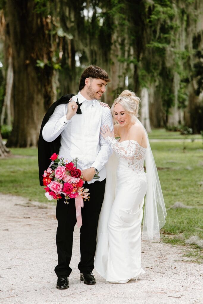 bride and groom wearing classic black and white wedding attire with a bold red and pink bouquet at an elopement at Kraft Azalea Garden in Winter Park, Florida, captured by Gracie May Photography