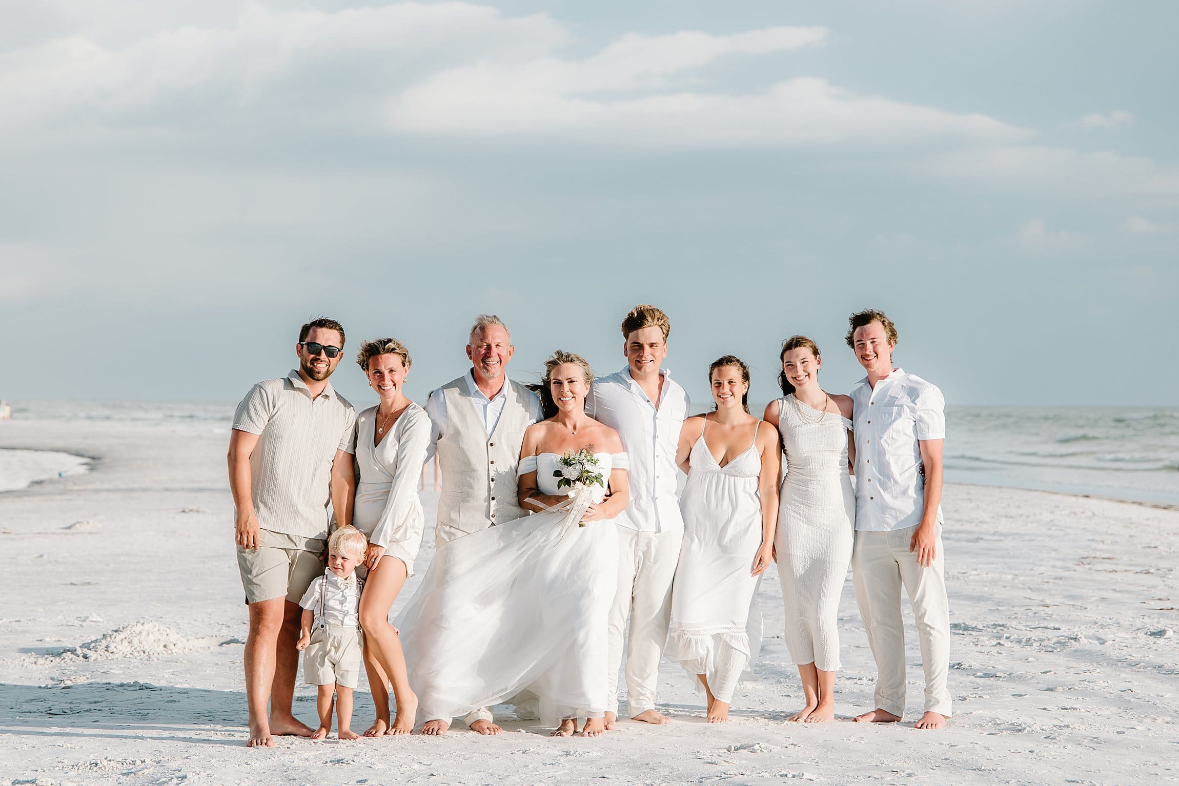 family wedding photo on a windy day on the beach at siesta key in sarasota florida