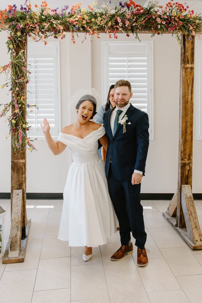bride and groom get married under a wooden arch with wildflowers in the ceremony room at St. Lucie County Clerk of Courts in Florida, captured by Gracie May Photography