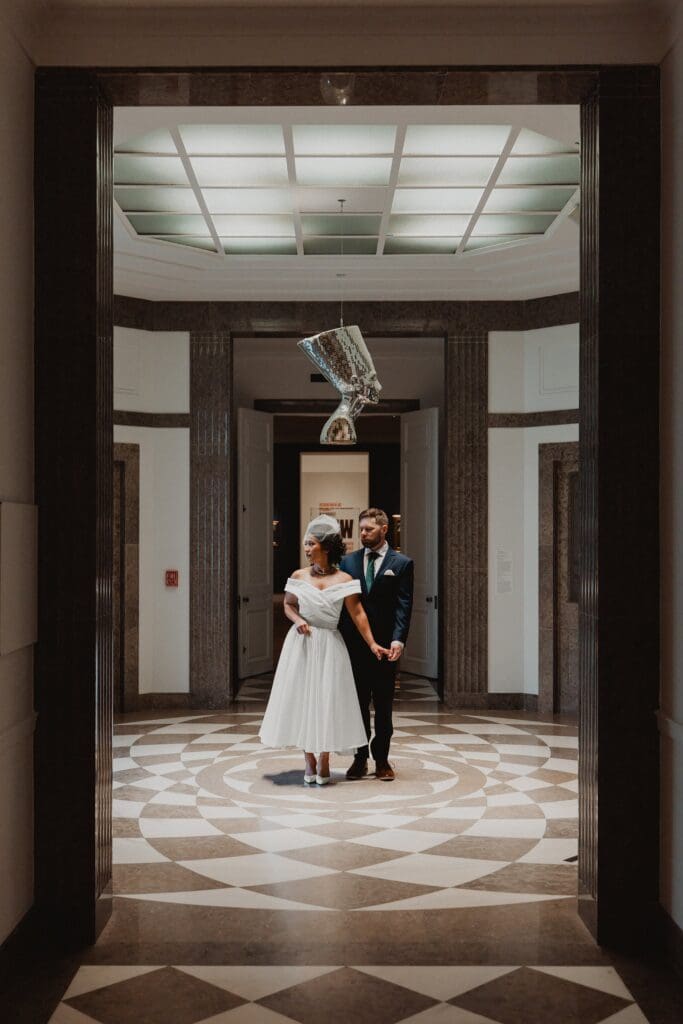 bride and groom stand holding hands in a rotunda with black and white checkered floors at the Norton Museum of Art in West Palm Beach, captured by Gracie May Photography