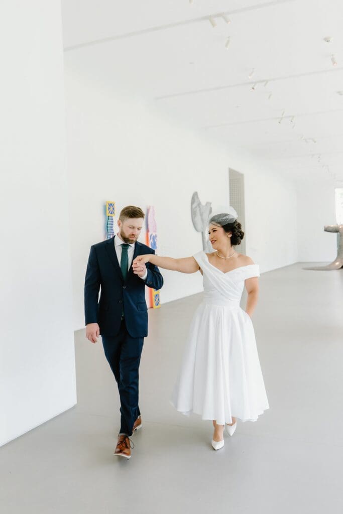 bride and groom walk playfully in a white modern art gallery room at the Norton Museum of Art in West Palm Beach, captured by Gracie May Photography