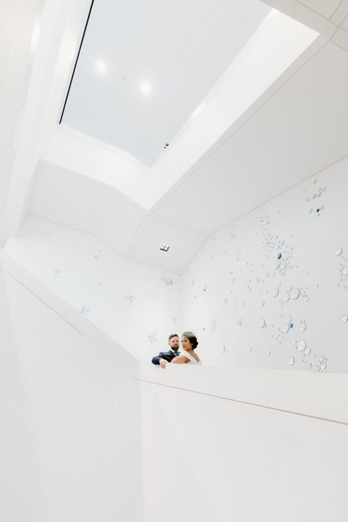 bride and groom stand on the stairs in a white modern art gallery room at the Norton Museum of Art in West Palm Beach, captured by Gracie May Photography