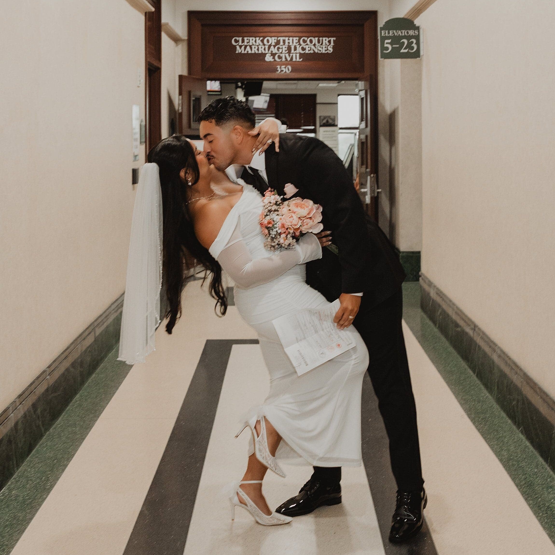 newly married couple kissing in the hallway of the orange county courthouse in orlando