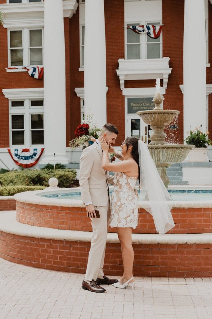 bride and groom kiss in front of the fountain outside of the historic Pasco County Courthouse in Dade City Florida during their outdoor wedding, captured by Gracie May Photography