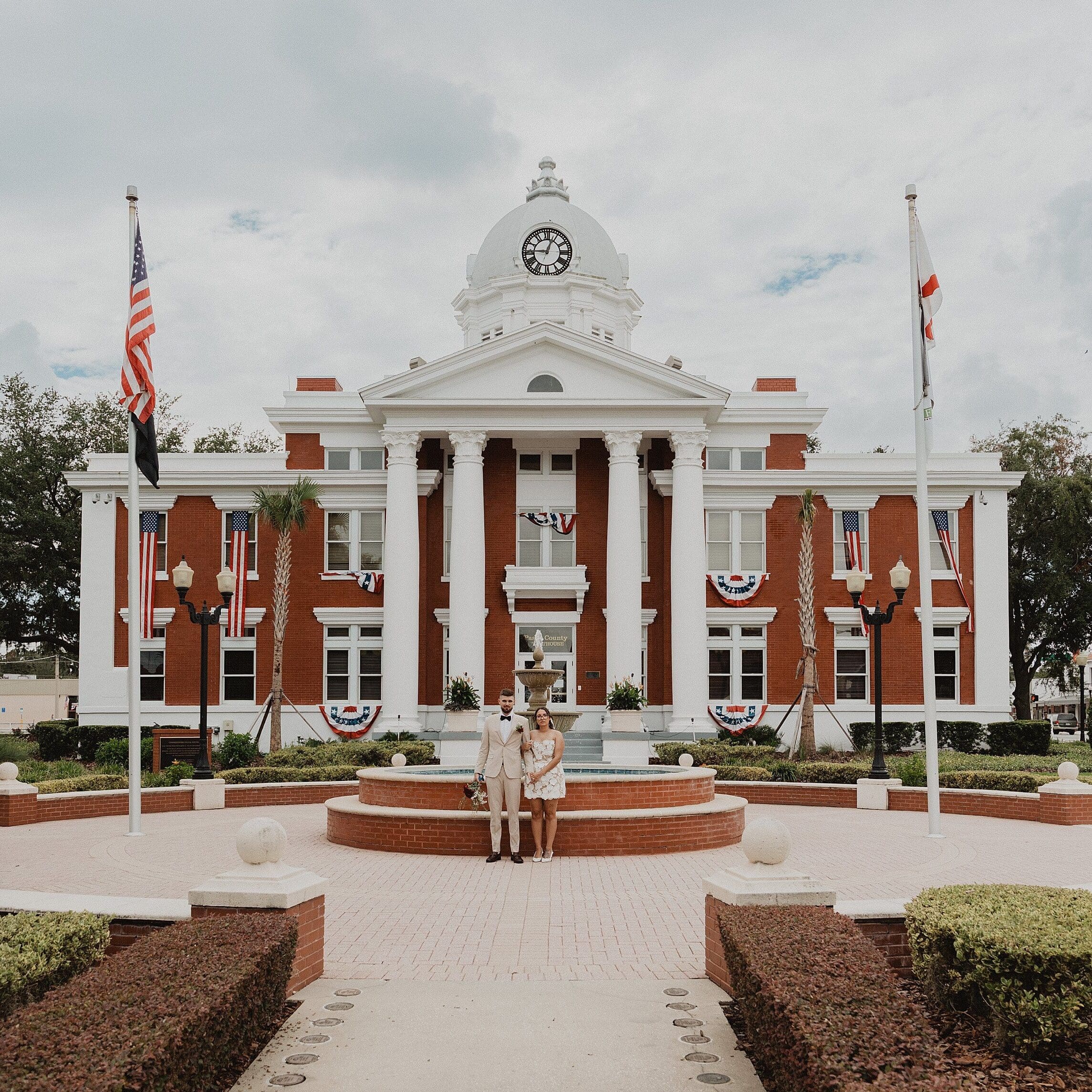 bride and groom leaning on the fountain outside of the historic Pasco County Courthouse in Dade City Florida after their outdoor wedding, captured by Gracie May Photography